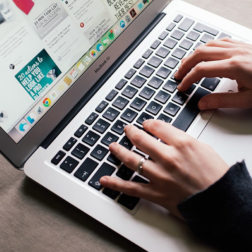 Person typing on a MacBook Air, engaging with Pinterest marketing content, reflecting digital marketing strategies and insights.