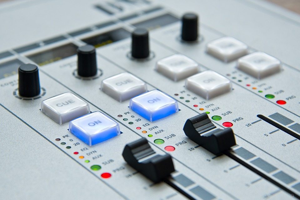 Radio mixing console with illuminated buttons and sliders, symbolizing radio advertising and media communication strategies.