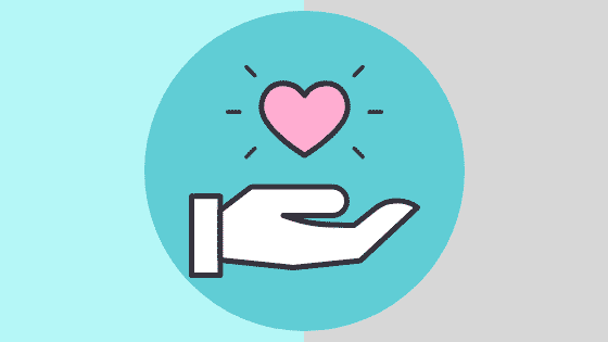 Hand holding a pink heart symbol, representing community involvement and giving back during the holiday season, relevant to marketing strategies for brand awareness.